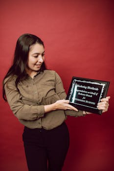 Young professional woman holding a business award plaque against a red background.