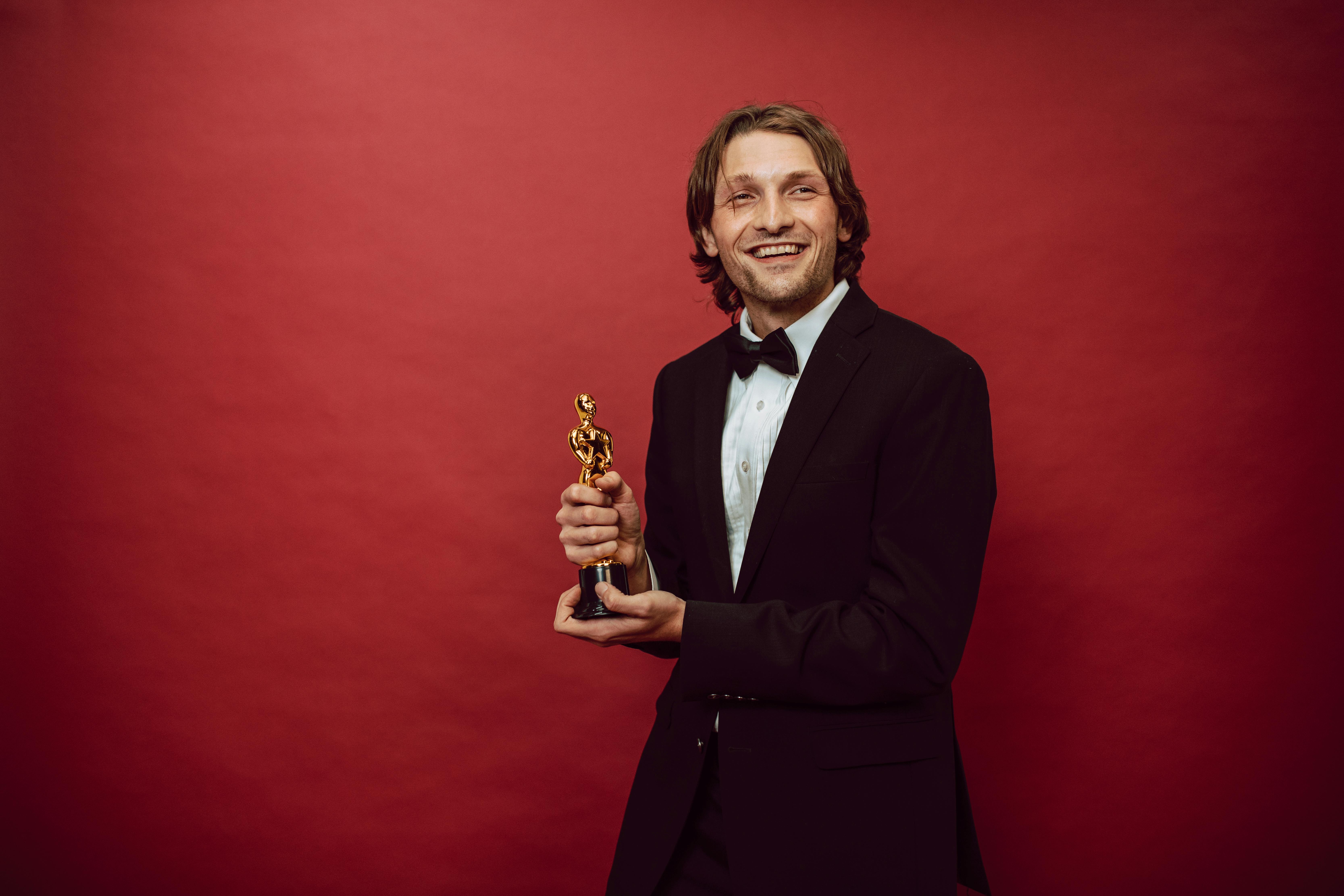 a proud actor holding his trophy