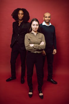 Portrait of diverse professionals standing against red background in studio.