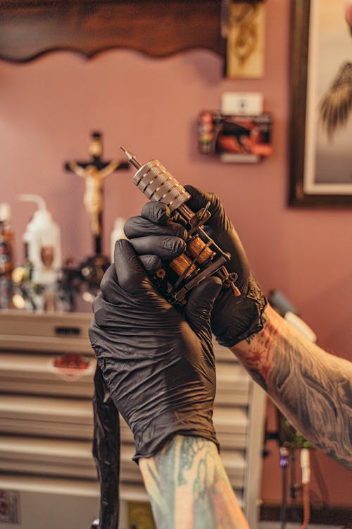 Free A Person Wearing Black Gloves Holding a Tattoo Machine Stock Photo