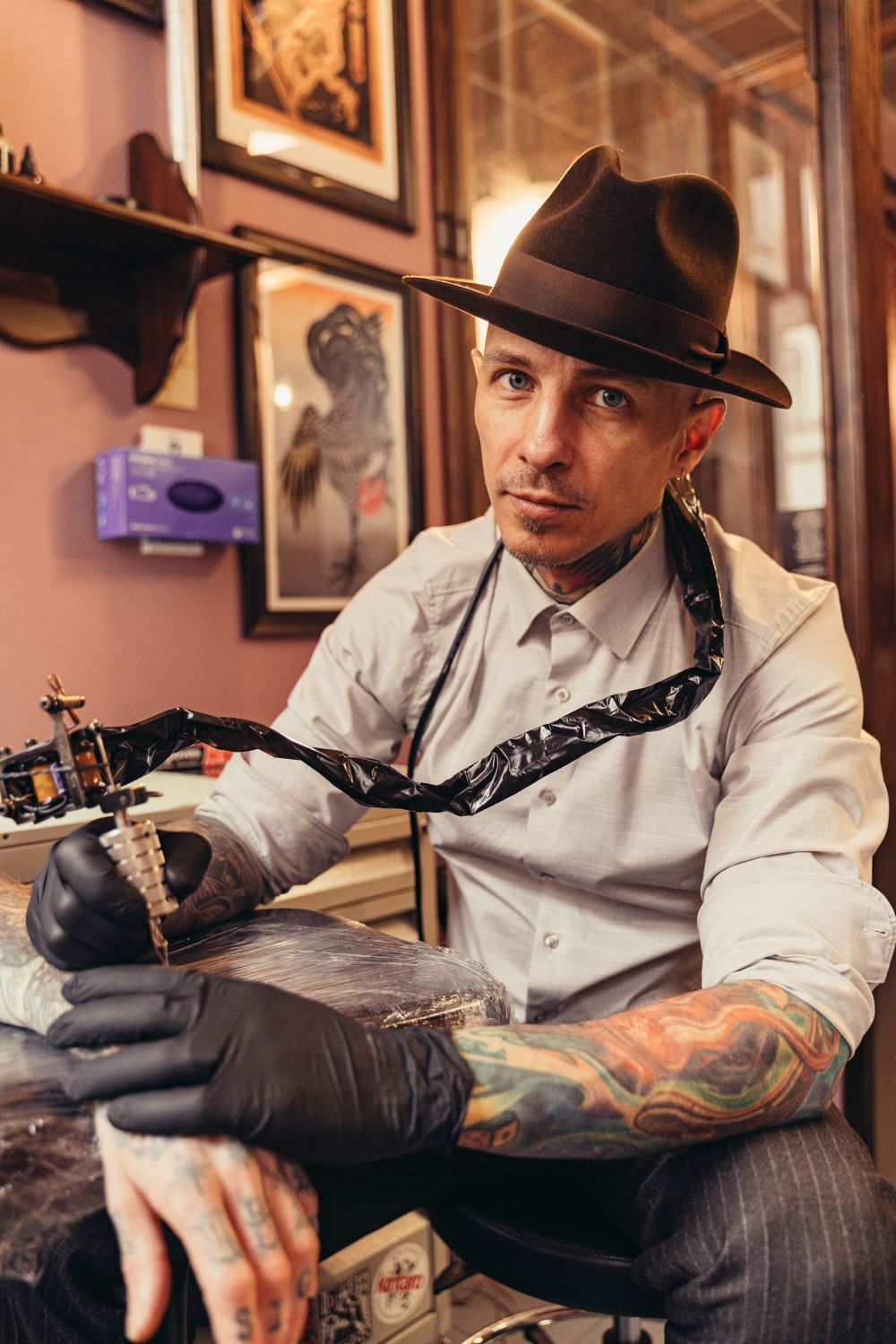 Nico Reyes in a fedora holding a tattoo machine