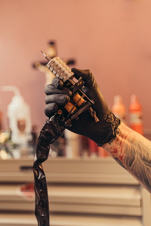 Free A Person Wearing a Black Glove Holding a Tattoo Machine Stock Photo
