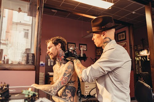 Free A Tattoo Artist Tattooing a Client's Neck Stock Photo