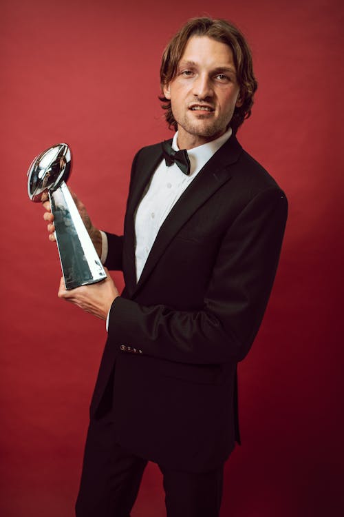A Man Holding a Football Trophy