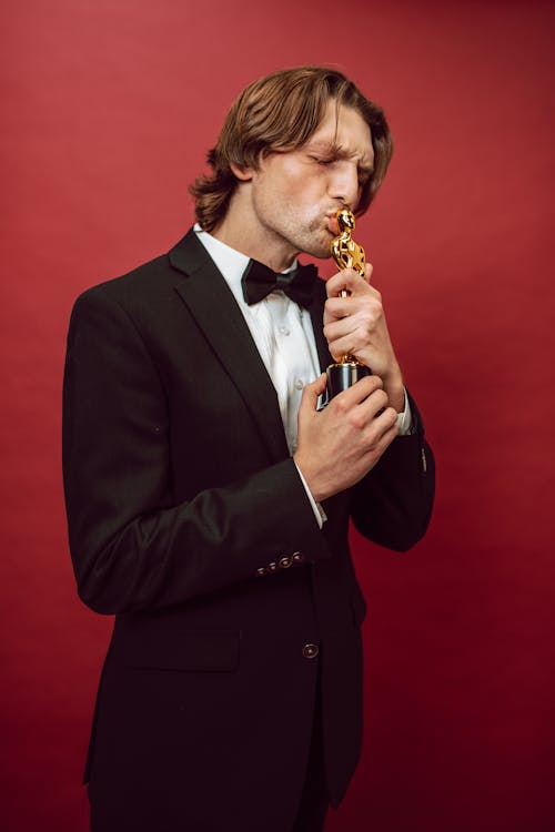 A Man in a Suit Kissing an Oscar