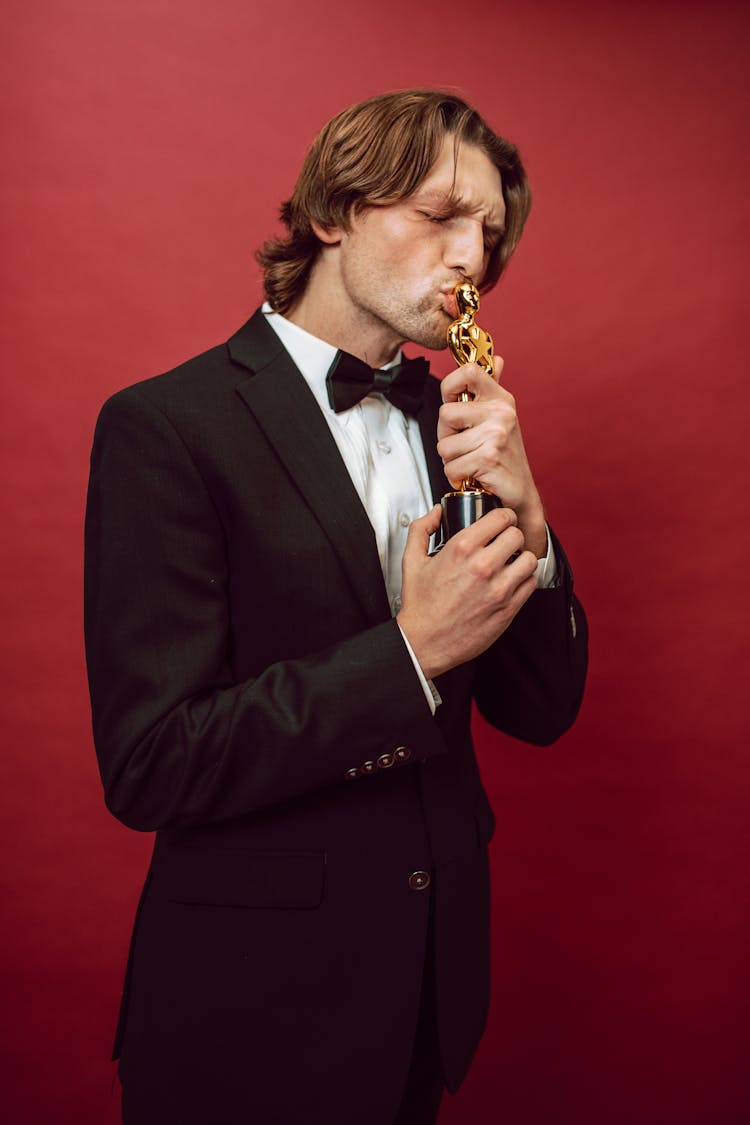 A Man In A Suit Kissing An Oscar