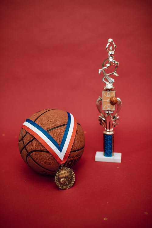 A Medal on a Basketball beside a Trophy