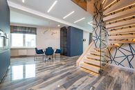 Staircase against decorative wall and table with armchairs on floor reflecting window in contemporary flat