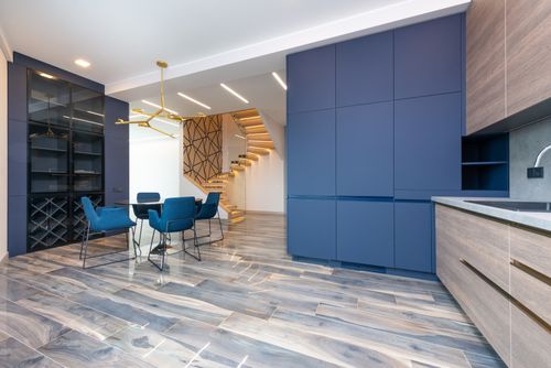 Free Contemporary kitchen with cabinets and table with armchairs against staircase on floor in light house Stock Photo