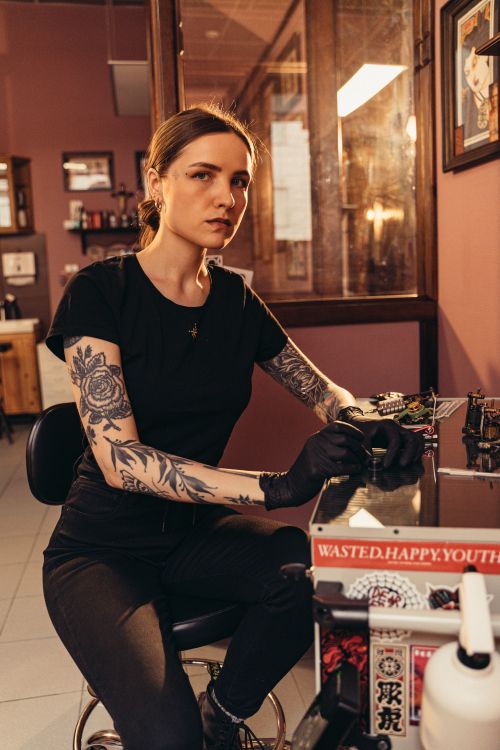 Free Tattoo artist in a cozy parlor setting, ready for tattooing with machine. Stock Photo
