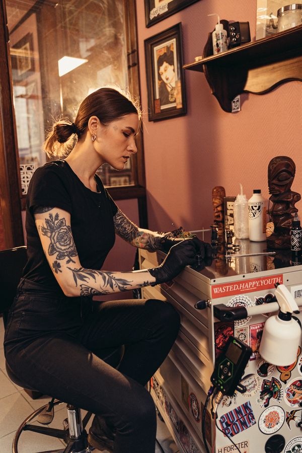 A No Regrets Tattoo artist concentrating on a piece in a warmly decorated studio