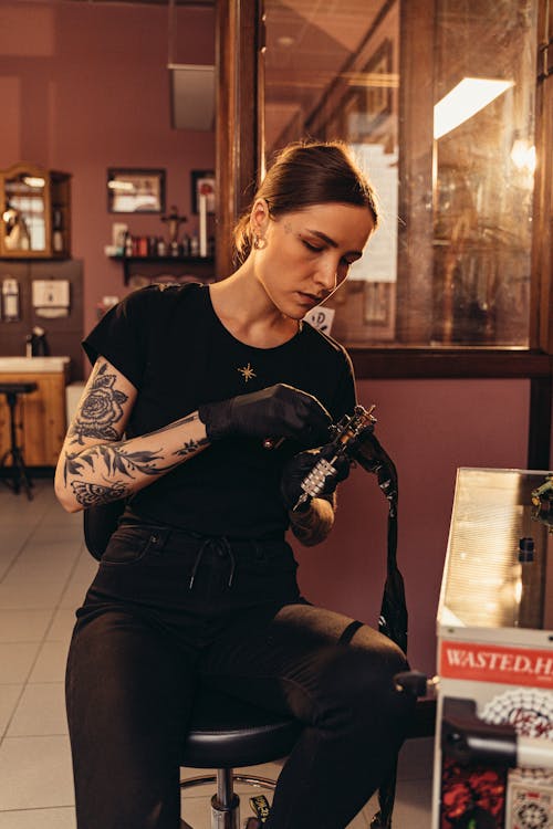 A Tattooed Woman Holding a Tattoo Machine