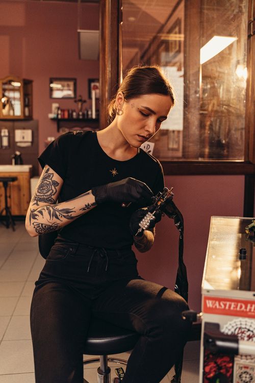 Free Tattoo artist working intently in a modern studio, showcasing intricate body art. Stock Photo