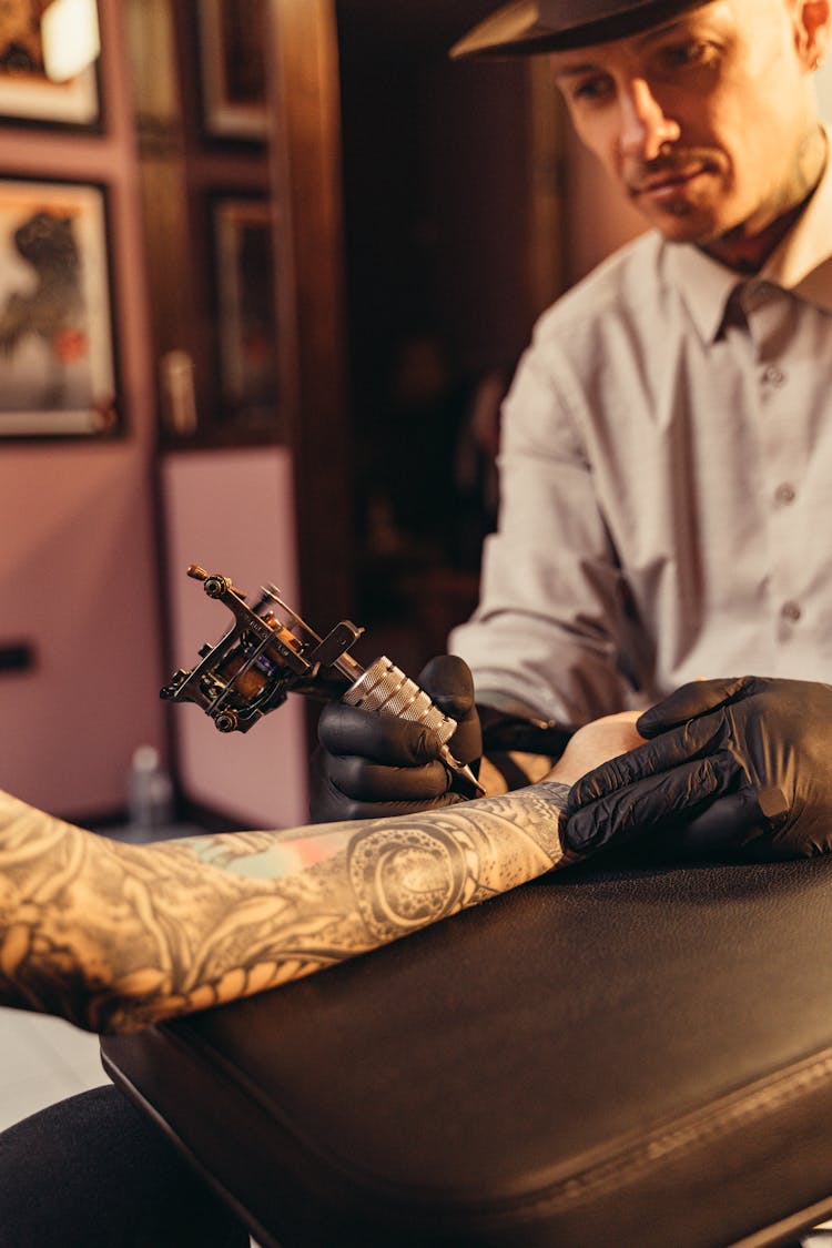 A Man Tattooing A Client's Arm