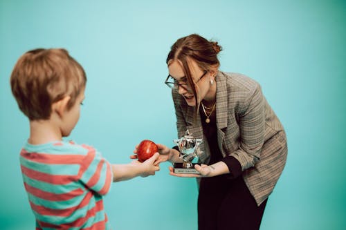 Free A Woman Giving an Apple and a Trophy to a Boy Stock Photo