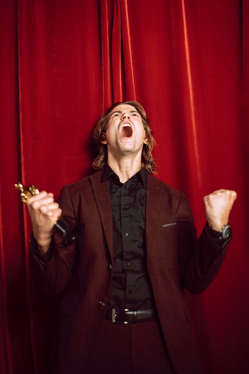 A Man in a Suit Celebrating While Holding an Oscar