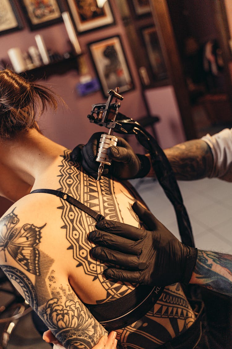 Person Tattooing A Woman On The Back