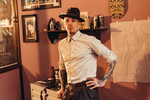 Free Man in Long Sleeves and Hat Standing Inside a Tattoo Shop Stock Photo