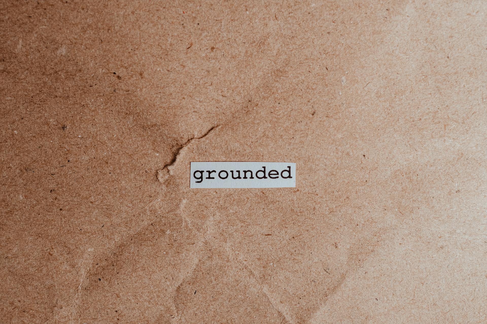 Textured brown surface with the word 'grounded', conveying stability and mindfulness.