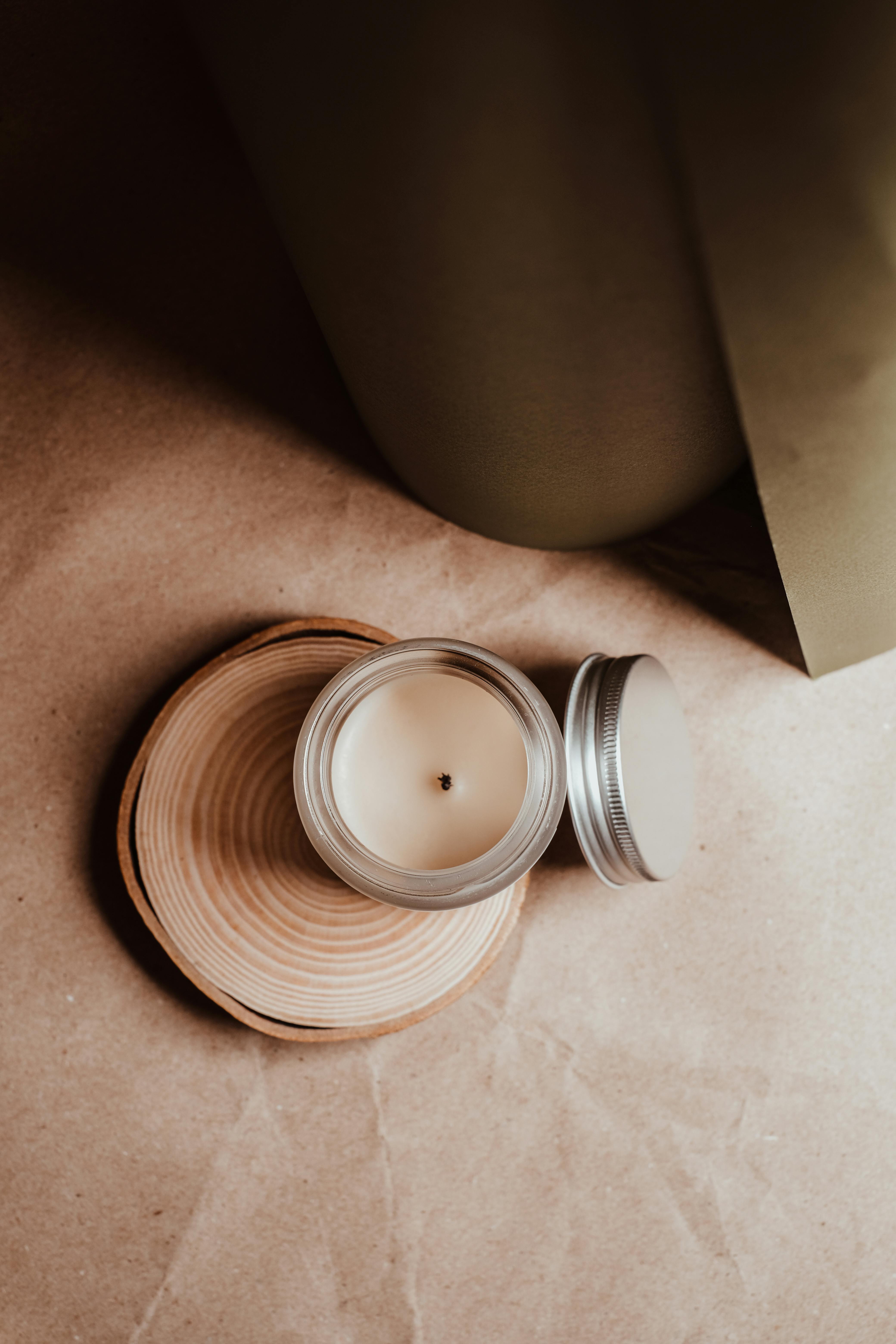 Top view of a candle in a glass jar on a wooden coaster, creating a cozy ambiance.