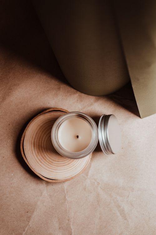 Free Top view of a candle in a glass jar on a wooden coaster, creating a cozy ambiance. Stock Photo