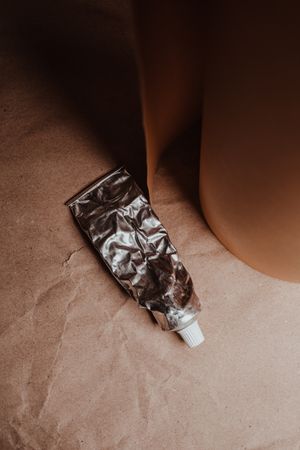 Crumpled metal tube on brown paper — photo by Vie Studio on Pexels
