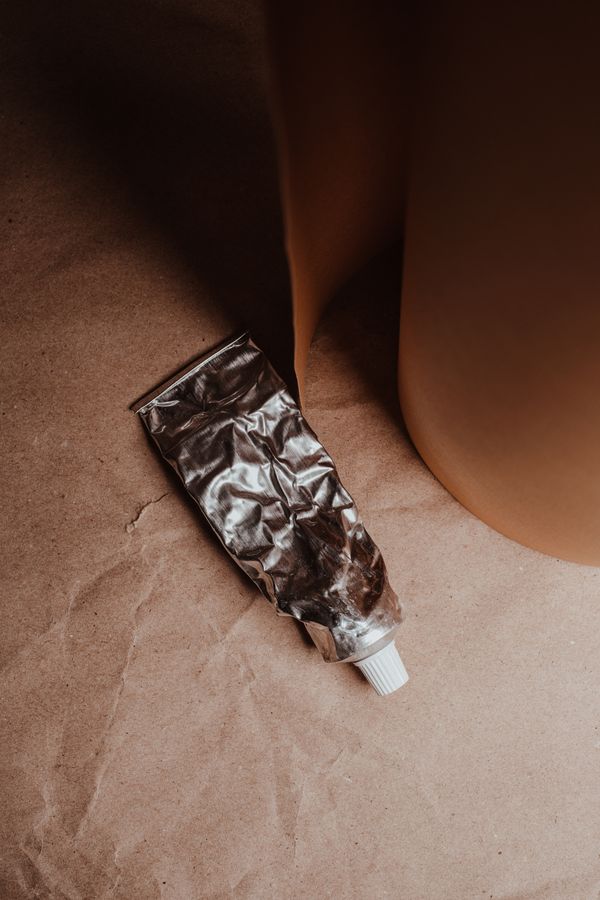 Crumpled metal tube on brown paper — photo by Vie Studio on Pexels
