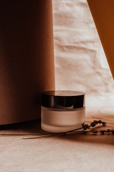 Aesthetic photo of a glass jar amidst elegant brown tones with dried lavender accents.