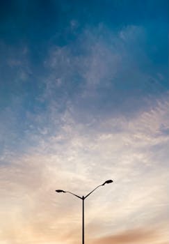 A dramatic vertical shot of a lamp post silhouette set against a twilight sky with vibrant colors.