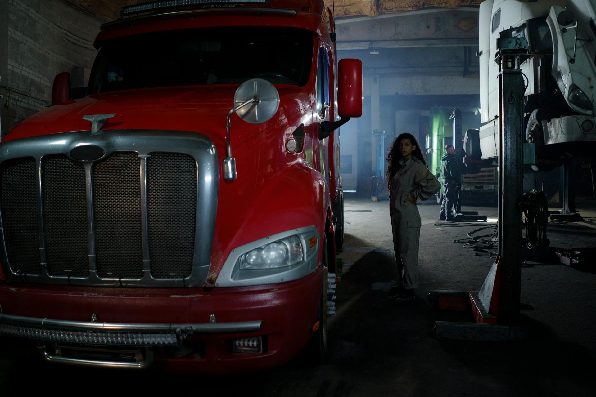 Curly Hair Woman Wearing Brown Longsleeve Playsuit Standing Beside Red and Silver Truck