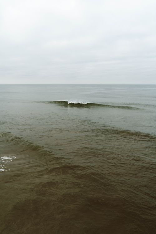 Free Serene ocean waves gently moving under a cloudy sky, evoking calm and peace. Stock Photo