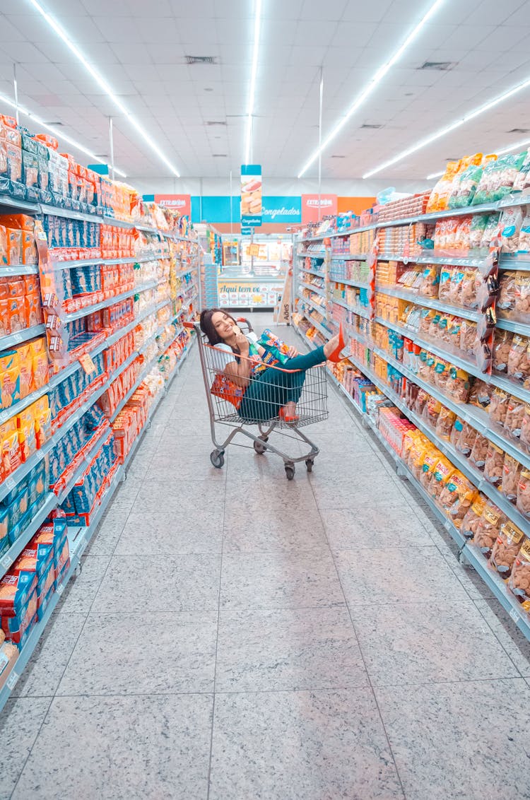 A Woman Inside The Shopping Cart At The Grocery Store