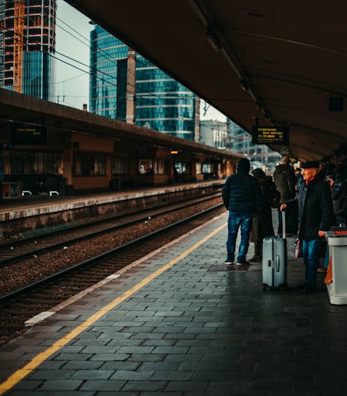 Photo of a Person with a Luggage Bag Waiting at a Train Station