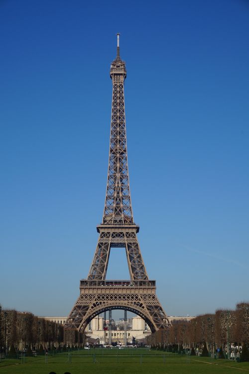 Free Iconic Eiffel Tower standing tall under a clear blue sky in Paris, showcasing its architectural beauty. Stock Photo