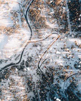 A stunning aerial view of a snow-covered forest in Utah during winter, highlighting the winding roads and scattered trees.