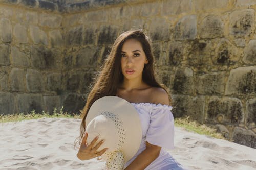 A Woman in White Off Shoulder Dress Sitting on the Sand