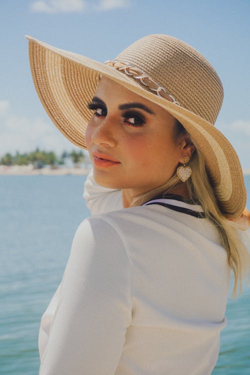A Woman in White Long Sleeves Looking Over Shoulder while Wearing a Hat