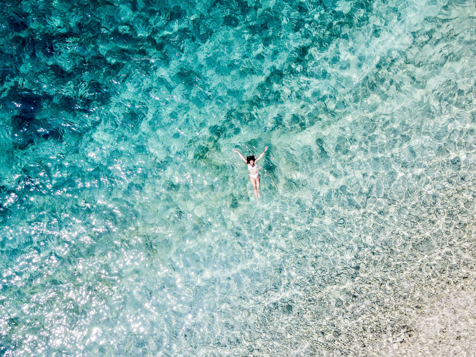 A woman swimming in the open sea, sunlight on the water