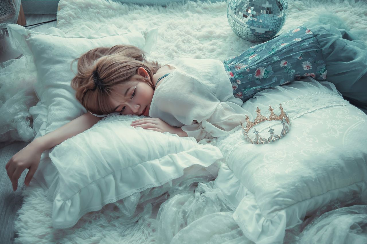 a serene girl laying on a bed surrounded by pillows exuding tranquilit