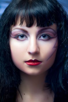 Close-up portrait of a woman with creative makeup and striking blue eyes.