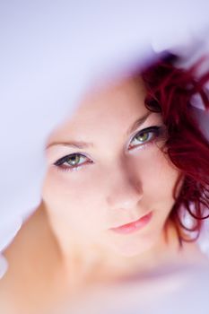 Artistic close-up portrait of a woman with striking eyes and red hair.