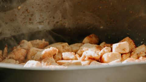 A close-up view of tofu cubes being cooked in a frying pan.