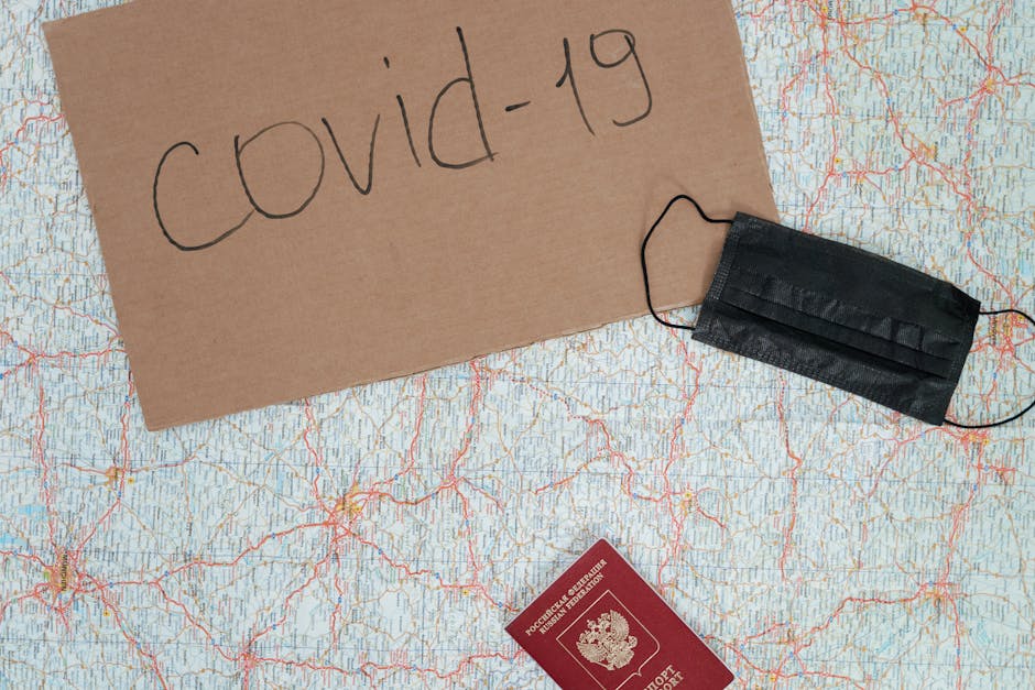 A placard reading 'covid-19', a map, face mask, and passport representing travel restrictions.