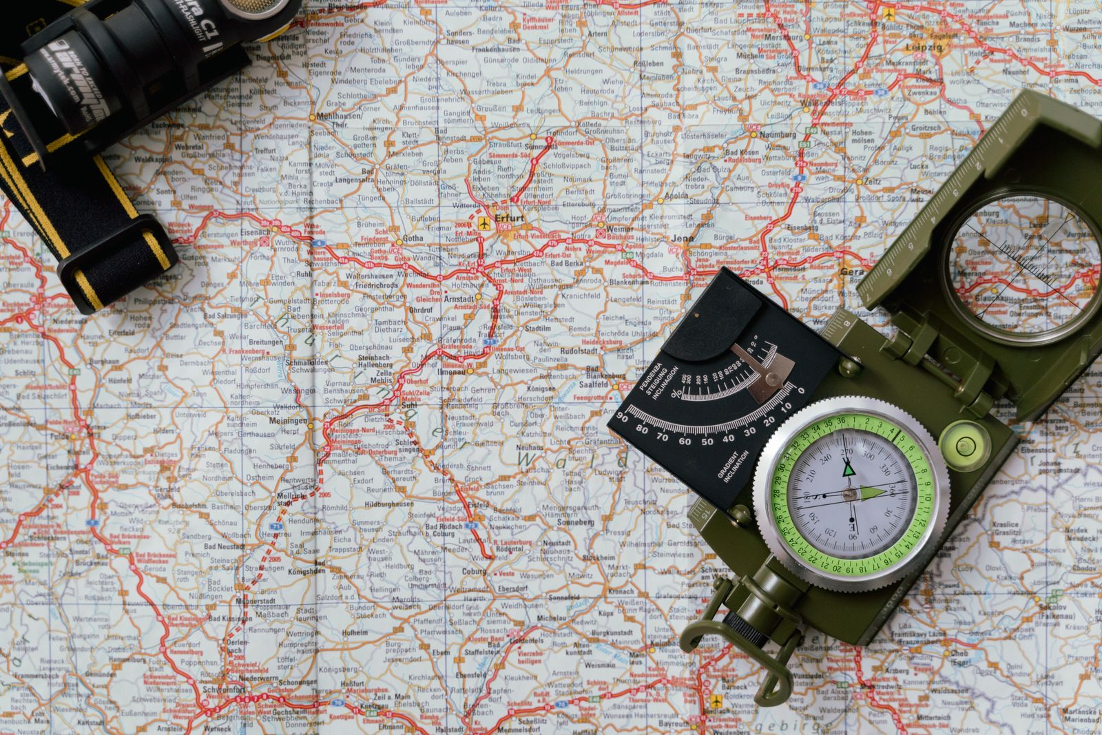 A navigational compass resting on top of a detailed paper map