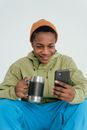 Man in Green Jacket Holding Silver and Black Tumbler