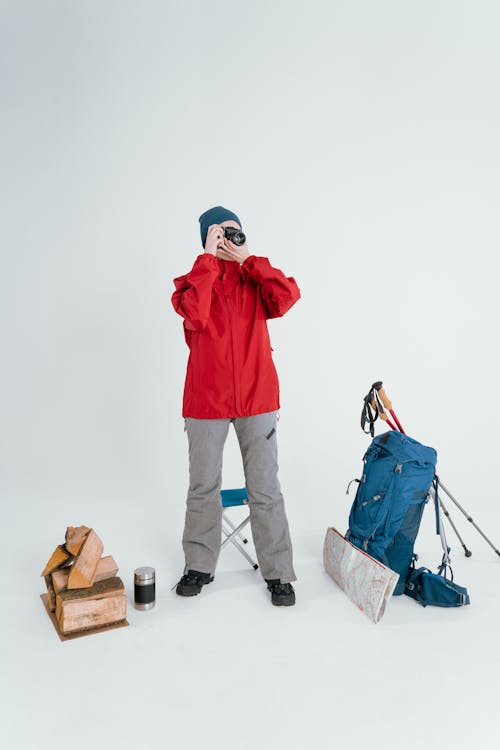 Free Person In Red Jacket With Packed Bags Looking Through A Camera Stock Photo