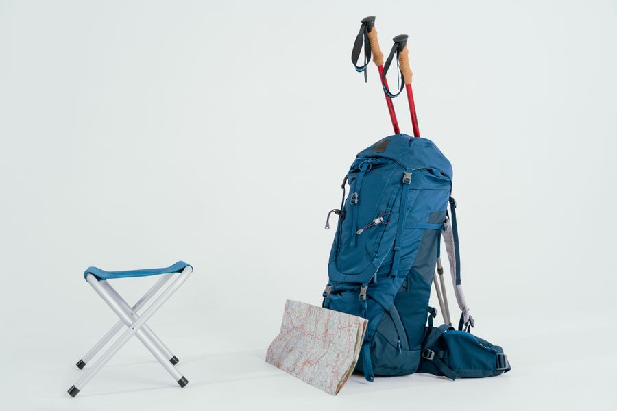 Blue fitness backpack with trekking poles on white