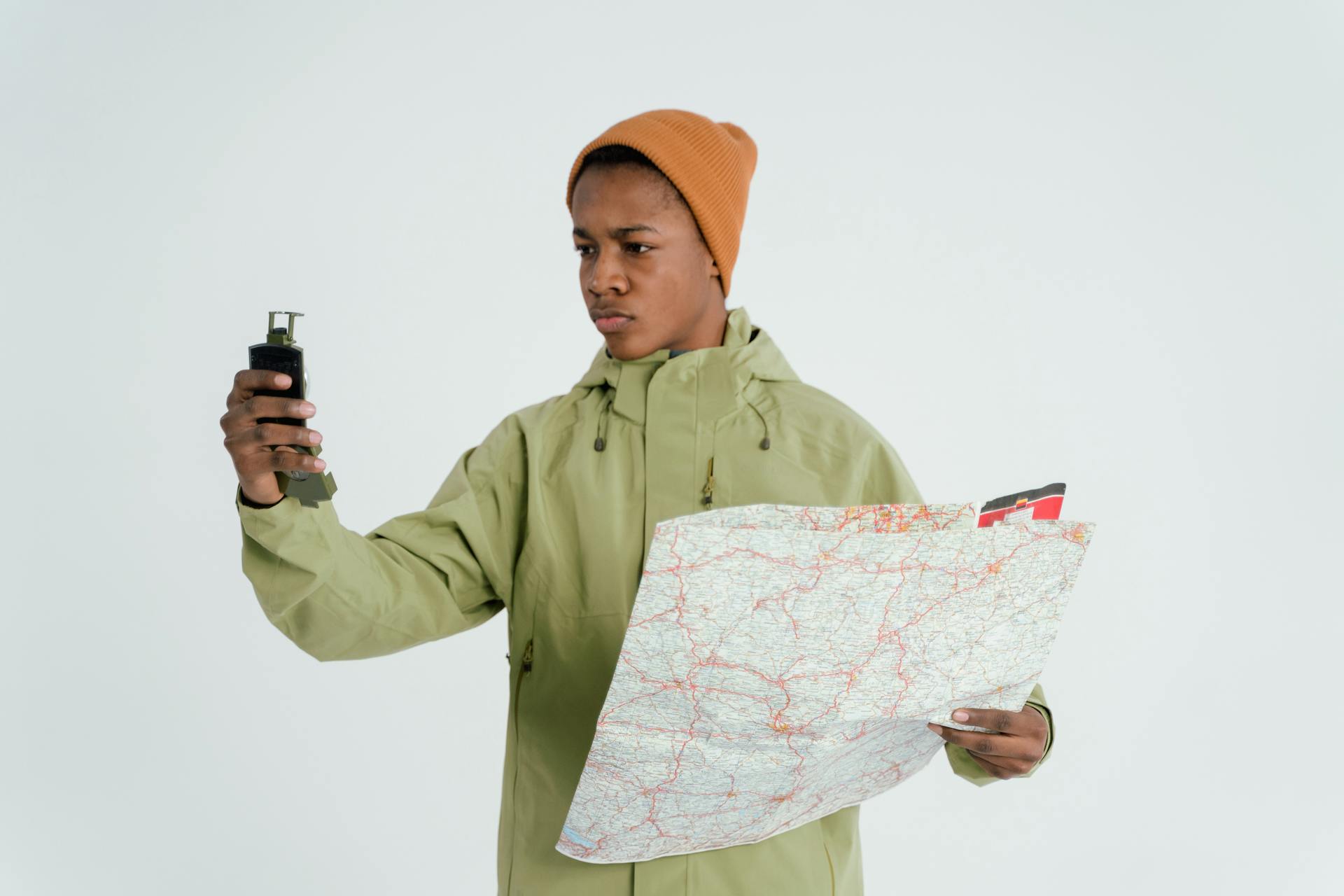 A Man in Orange Knit Cap Holding a Compass and a Map