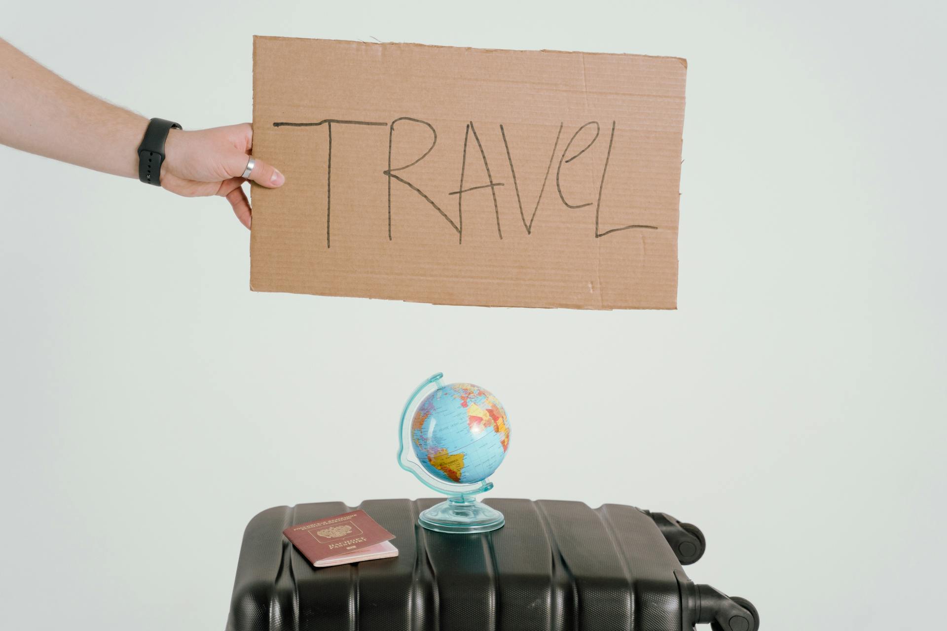 A Person Holding a Cardboard with a  Handwritten Travel  Sign