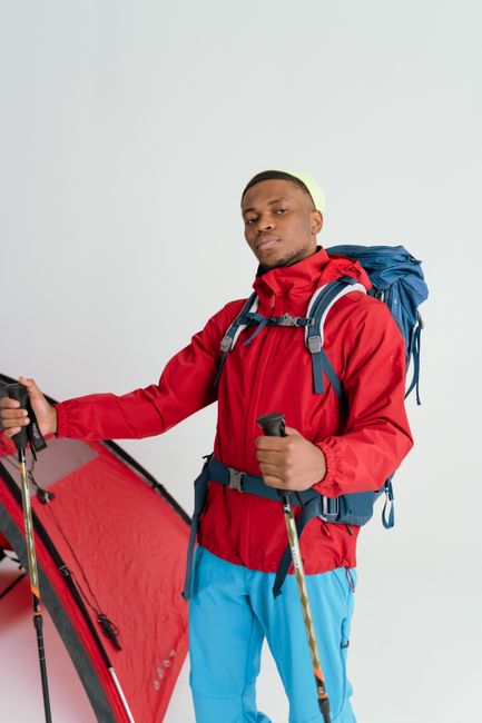 Spring backpacking gear laid out on a tarp with a lightweight tent, rain jacket, and trail snacks among wildflowers